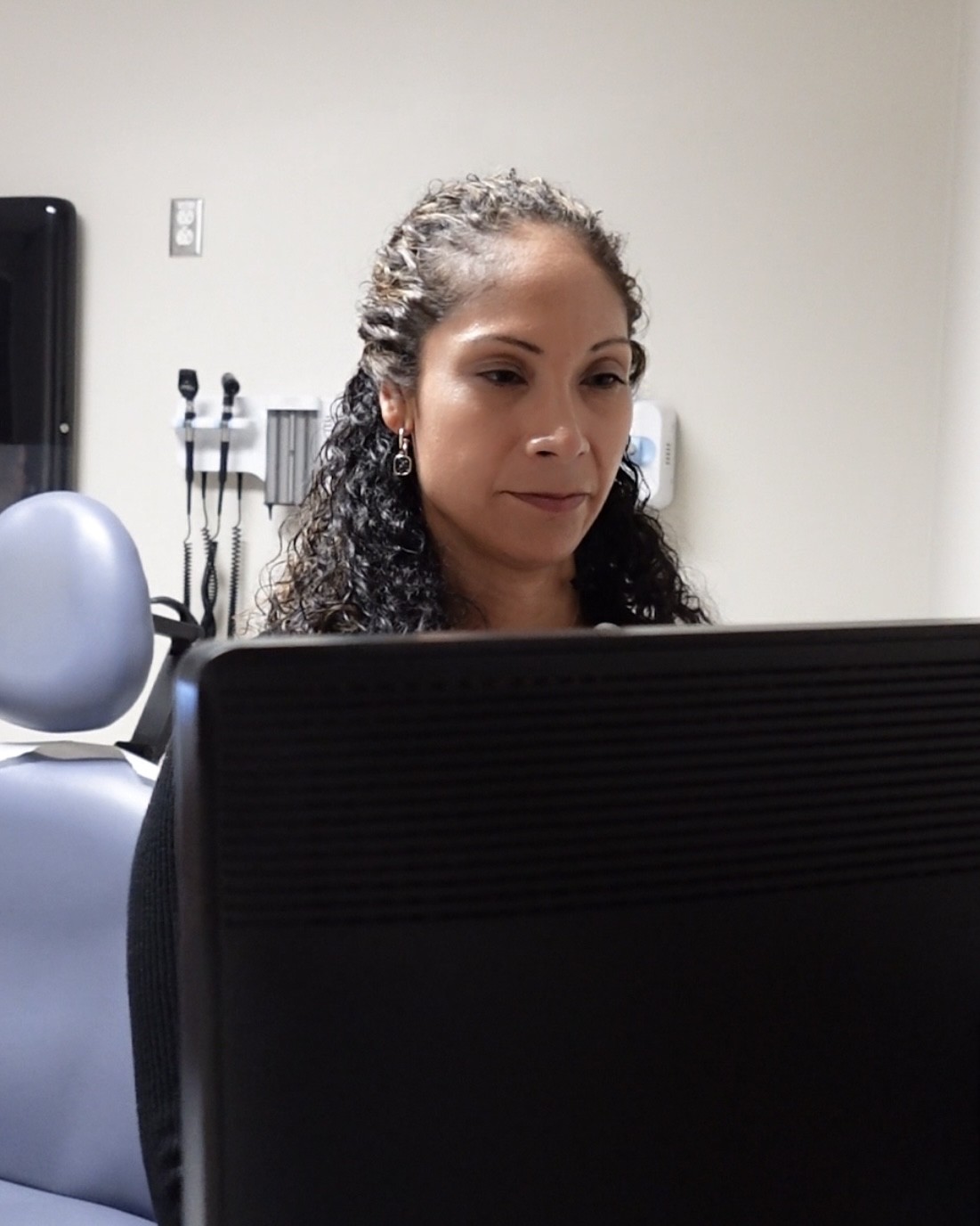Dr. Bernice McCoy working at a computer in a clinical setting.